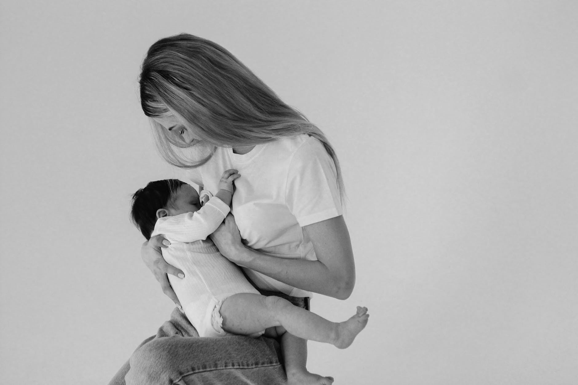 grayscale photo of a mother breastfeeding her child