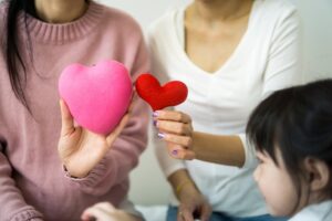 crop women with decorative hearts sitting near child